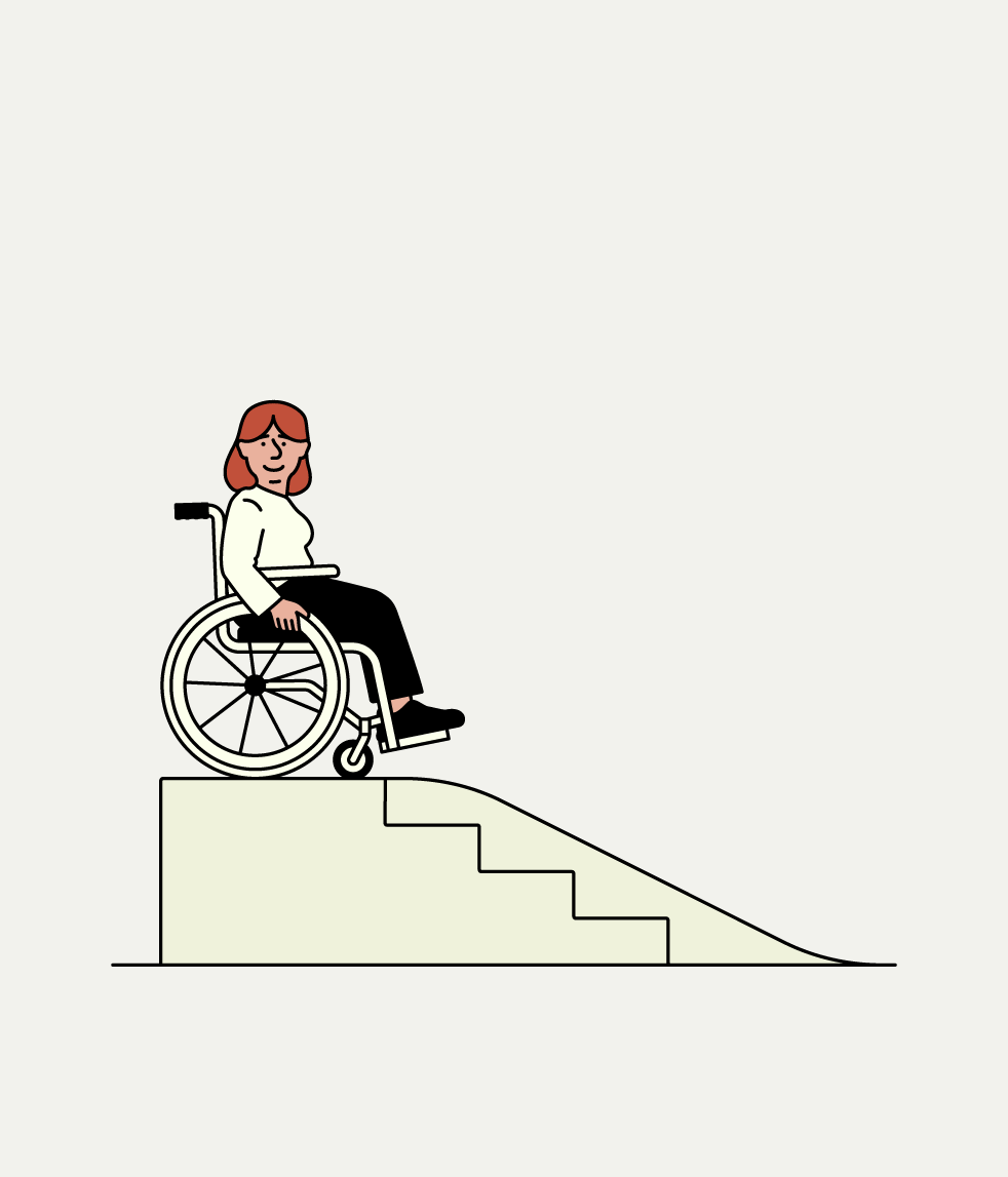Persona en cadira de rodes davant d’una rampa accessible al costat d’unes escales.