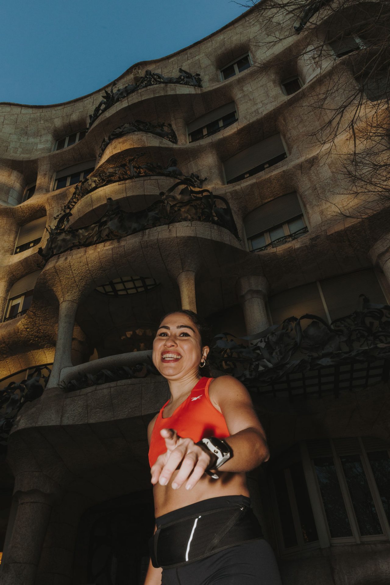 Una dona amb un top taronja corre davant la façana de La Pedrera.